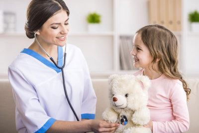 Young smiling female doctor and her little patient  with teddy bear