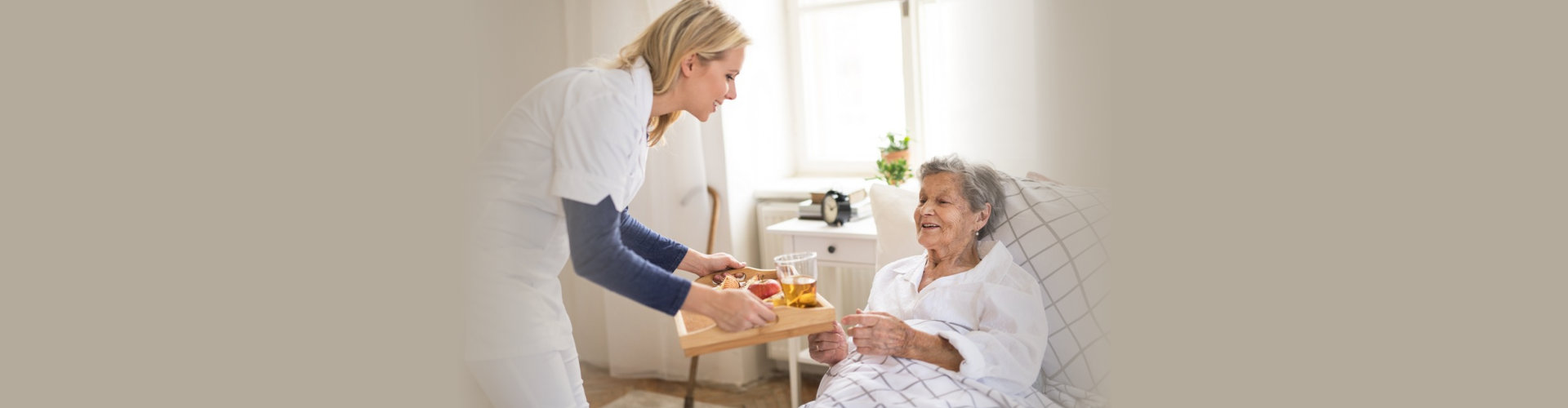 young health visitor bringing breakfast to a sick senior women